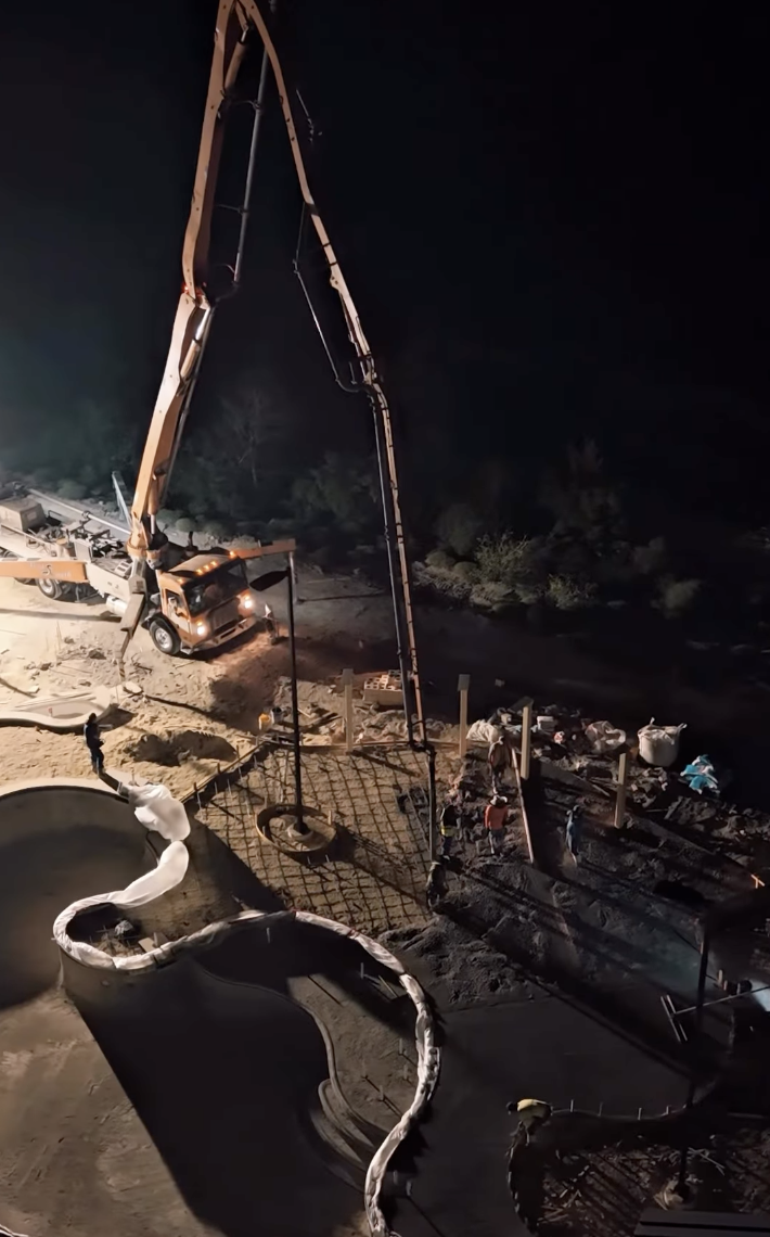 Concrete pump and crew placing a complex slab at night